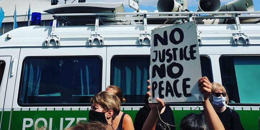 Menschen protestieren vor einem Polizeiauto