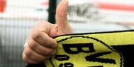 Eine hochgehaltener Daumen mit einem Schal des BVB Dortmund.