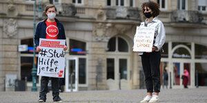 zwei Studierende mit Mundschutz und Protestplakaten
