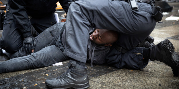 Polizisten drücken einen Mann zu Boden.