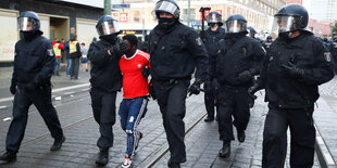 Ein schwarzer Mann wird von der Polizei abgeführt.