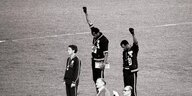 Zwei schwarze Sportler stehen auf dem Siegerpodest und recken die Fäuste