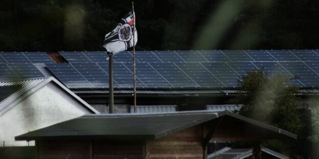 über einem Dach mit Solarpaneelen weht eine Reichskriegsflagge