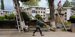 Ein Kind trägt eine Leiter auf einem Friedhof in Sucre.