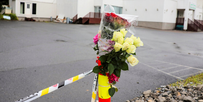 Blumen an einer Polizeiabsperrung.