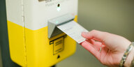 Eine Hand entwertet ein Ticket an einem Automaten