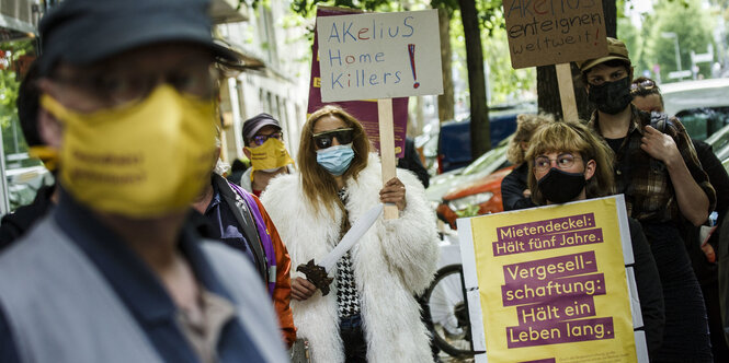 menschen mit Maske halten plakate für das Volksbegehren deutsche wohnen enteignen hoch