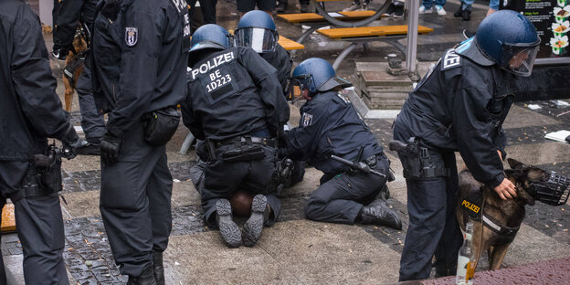Mehrere Polizisten knien auf einem Schwarzen Mann, während sie ihn festnehmen
