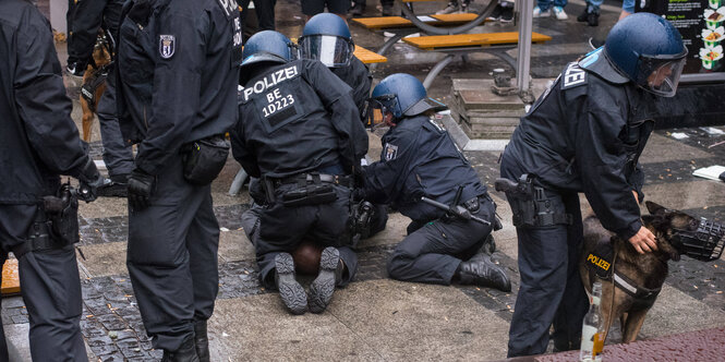 Mehrere Polizisten knien auf einem Schwarzen Mann, während sie ihn festnehmen