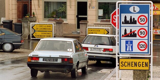 Autos neben einem Schild mit Verkehrsregeln in Luxemburg und dem Ortshinweisschild Schegen