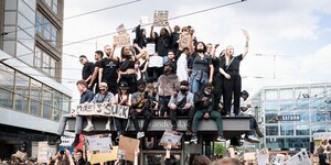 Dutzende Menschen ssitzen auf einem U-Bahnaufzug und halten Protestschilder hoch
