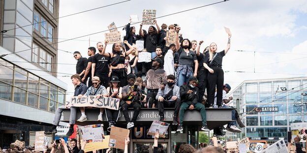 Dutzende Menschen ssitzen auf einem U-Bahnaufzug und halten Protestschilder hoch