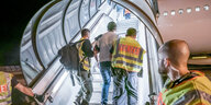 Polizeibeamte begleiten einen Afghanen auf dem Flughafen Leipzig-Halle in ein Charterflugzeug
