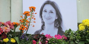 Bild der ermordeten Journalistin Galizia steht an einer Wand und ist mit Blumen umgeben