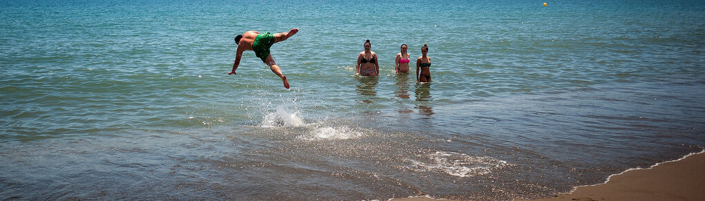 Mann springt ins Wasser, 3 Frauen schauen ihn an