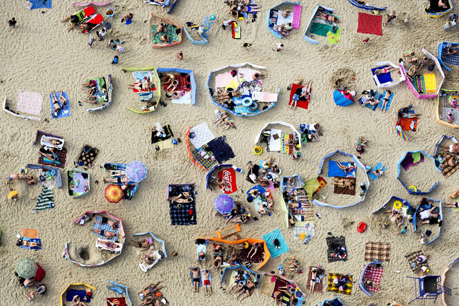 Menschenmenge mit vielen Strandutensilien im Sand