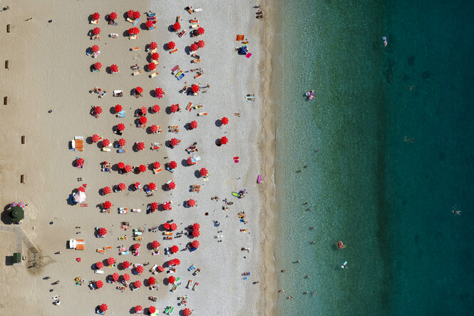 Eine Menge rote Sonnenschirme und das blaue Meer