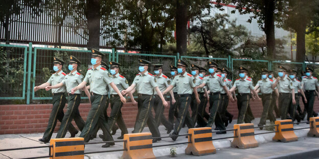Eine Gruppe Polizisten marschiert an einer Straße.