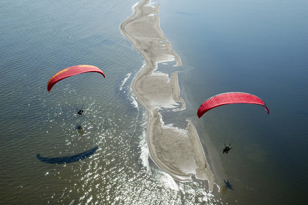 Zwei rote Paragliderüber dem glitzernden Wasser