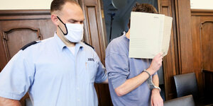 Ein Angeklakter mit verdeckten Gesicht vor Gericht.
