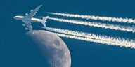 Ein Flugzeug mit langen Kondensstreifen scheint den Mond zu berühren