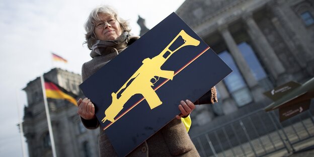 Frau hält Plakat mit Maschinengewehr