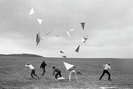Vier Männer und eine Frau werfen Dreiecke in die Luft, die wie Drachen steigen