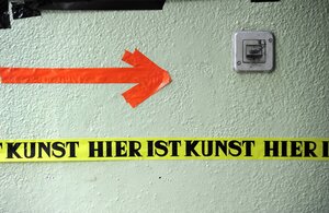 Ein ornagener Pfleil und ein gelbes Klebeband mit dem schwarzen Schriftzug "Hier ist Kunst" weisen auf eine kleine Galerie in der Neuköllner Wissmannstraße hin Ein ornagener Pfleil und ein gelbes Klebeband mit dem schwarzen Schriftzug "Hier ist Kunst" weisen auf eine kleine Galerie in der Neuköllner Wissmannstraße hin