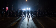 Polizist*innen und Demonstrant*innen laufen im Dunkeln über eine Straße