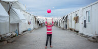 Ein Mädchen in einem Containerlager für Flüchtlinge wirft einen Ball hoch
