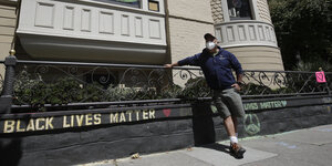 Mann vor einem Haus "Black Lives Matter"mit Kreide aufgemalt