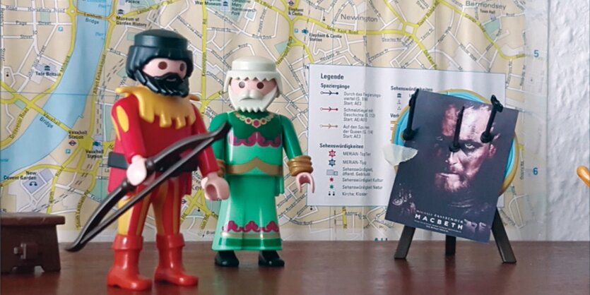 Zwei Playmobilfiguren stehen vor einer Zielscheibe mit einem Mac Beth-Plakat