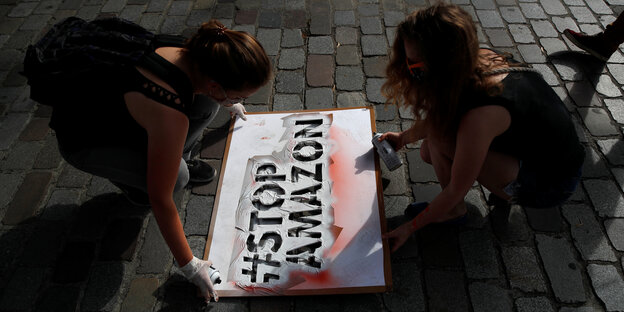 Frauen legen ein Plakat auf eine Straße