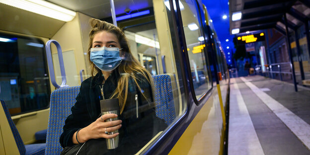 Frau mit Maske in einer Bahn