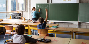 Zwei Kinder mit Lehrerin in Klassenraum