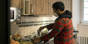 Ein kochender junger Mann in einer Gemeinschaftsküche