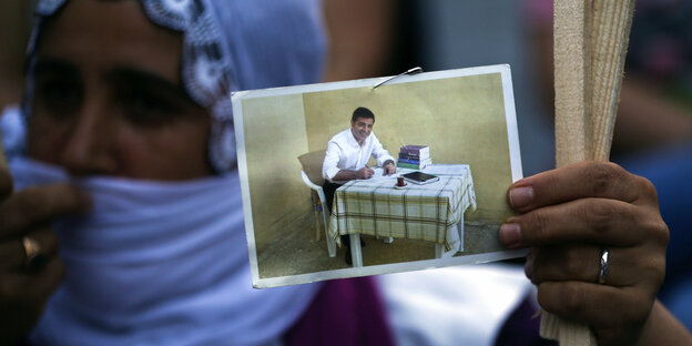 Frau hält ein Foto von Demirtas, der am Tisch sitzt