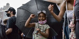 Ein Mädchen ballt die Faust unter einem Regenschirm