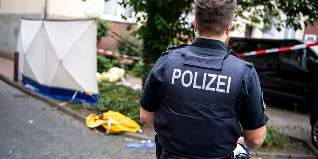 EIn Polizist steht am mittlerweile abgesperrten Ort des tödlichen Schusses in Bremen Gröpelingen