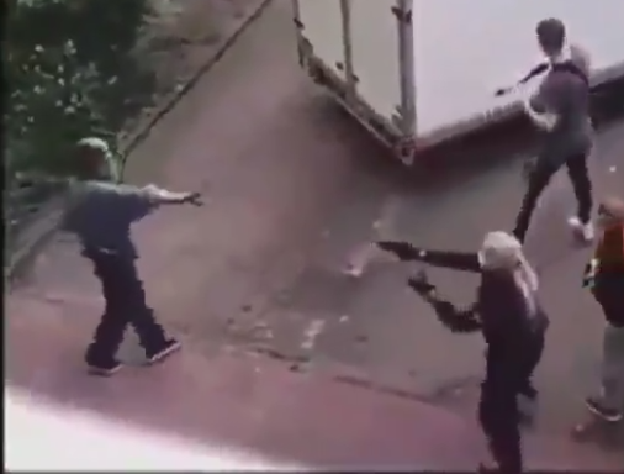 Screenshot aus dem Video: Der Mann, der später erschossen wird, geht mit ausgestreckter Hand auf die Polizist:innen zu; eine Polizistin zielt mit ihrer Waffe auf ihn Screenshot aus dem Video: Der Mann, der später erschossen wird, geht mit ausgestreckter Hand auf die Polizist:innen zu; eine Polizistin zielt mit ihrer Waffe auf ihn