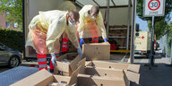 Zwei Rot-Kreuz-Mitarbeiter laden Kartons aus einem Lkw