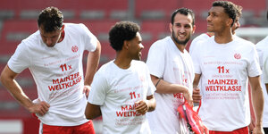 Mainzer Spieler feiern in T-Shirts ihren Klassenerhalt, auf denen steht: 8x Meister? Langweilig. 11x Drin bleiben? Mainzer Weltklasse"