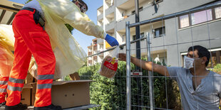 Ein Mitarbeiter des Roten Kreuzes reicht Wasser an einen Anwohner