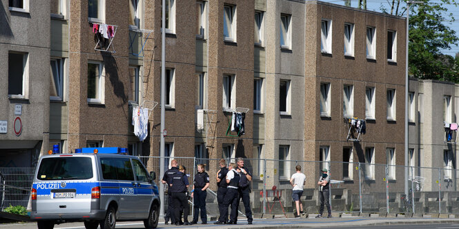 Vor einem Haus stehen Polizisten