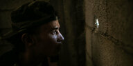 Ein Soldat schaut durch ein Loch in einer Wand