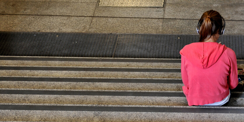 Junger Mensch sitzt allein auf einer Treppe