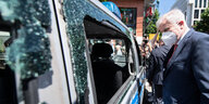 Bundesinnenminister Horst Seehofer (CSU) betrachtet ein beschädigtes Polizeiauto