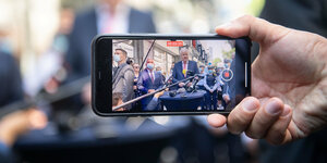 Der Bildschirm eines Smartphones zeigt eine Pressekonferenz von Horst Seehofer im Freien