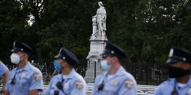 Polizisten vor einer Kolumbus-Statue