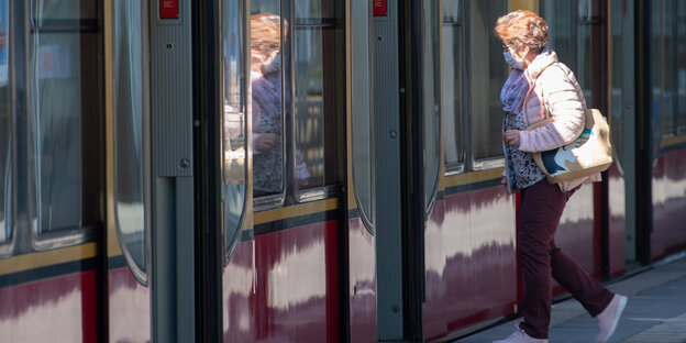 Eine Frau mit Maske betritt eine S-Bahn